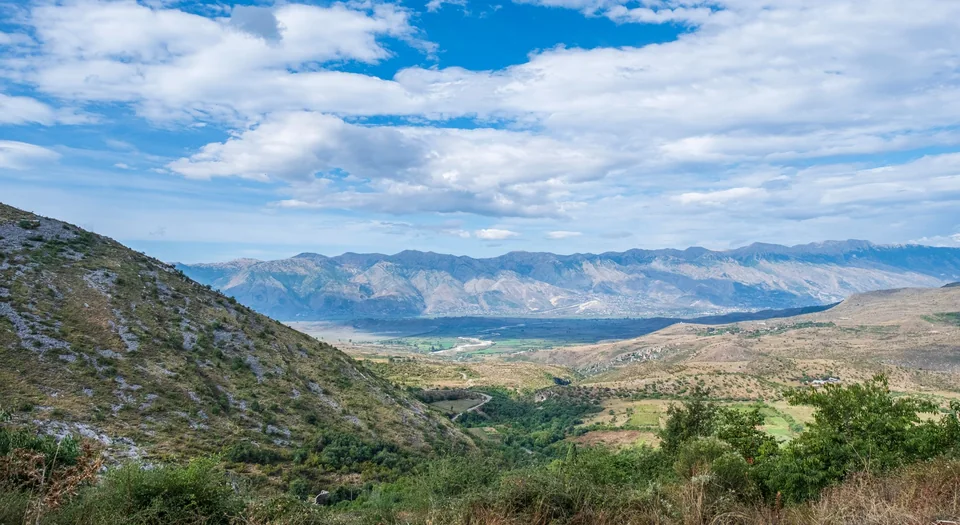 A wide valley and mountain ranges in the Albanian countryside