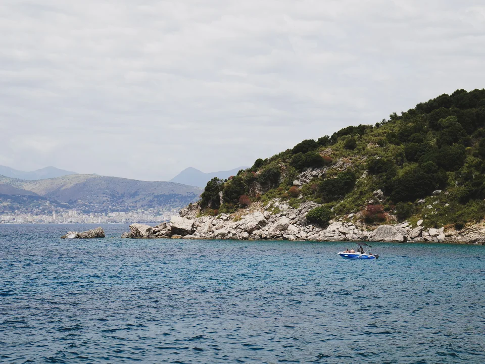 A green headland on the coast at Sarandë with the town across the water