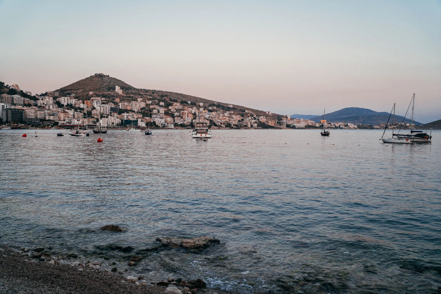 Boats in Sarandë bay below the hillside town at dusk